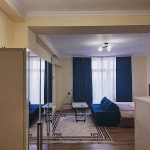 sala de estar con sofá azul y cama en Rusel Hotel en Aktau