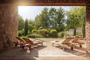 a patio with three lounge chairs and a pond at Golf & Spa Kunětická Hora in Dritec