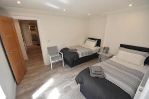 um quarto com duas camas e uma cadeira. em Modern Apartment near City Centre and The Bay em Cardiff