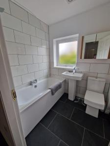 a white bathroom with a tub and a sink at Riverside home. 3 bedroom. Free parking. 10 mins to Newcastle City Centre in Dunston