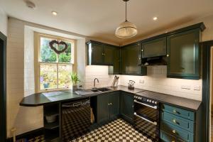 a kitchen with green cabinets and a window at Hazelbank, sleeps 10, on the shores of Loch Fyne in Cairndow