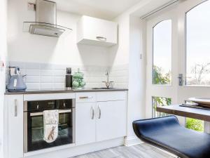 una cocina con armarios blancos y horno negro en Meadow View-uk34416, en Cheddar