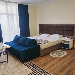 Rusel Hotel في أكتاو: غرفة نوم بسرير كبير وأريكة زرقاء