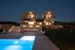 dom z basenem przed nim nocą w obiekcie Family & Golf VILLA LAGUNA TOWERS Gialova Navarino w mieście Gialova