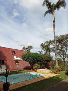 uma piscina em frente a uma casa com uma palmeira em Casa de campo, charme e aconchego em cond. fechado em Atibaia