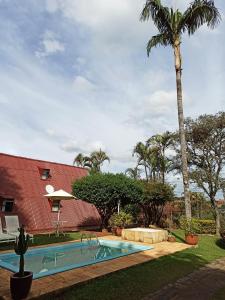 a swimming pool in front of a house with a palm tree at Casa de campo, charme e aconchego em cond. fechado in Atibaia