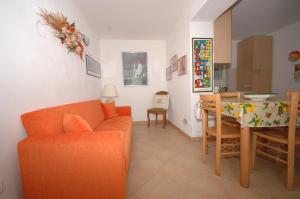 un soggiorno con divano arancione e tavolo di Pozzo al Moro a Marina di Campo