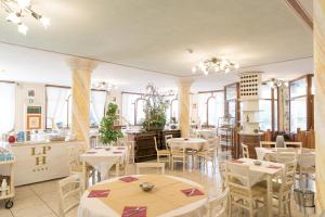 a restaurant with white tables and chairs and windows at Appartamenti La Vecchia Posta - 50 mt dal Mare in Marina di Grosseto