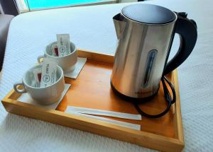 a coffee pot and three cups on a wooden tray at Hotel Perla in Benidorm