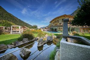 a house with a pond in front of a building at Hotel Römerhof in Fusch an der Glocknerstraße