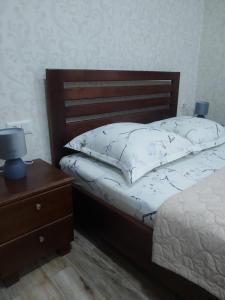 a bedroom with a bed with a wooden headboard and a table at Apartments on Akhalubani St 2 in Tbilisi City