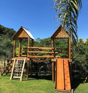 a wooden play structure with a ladder in the grass at Casarão Biazolli in Farroupilha