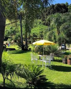 a table and chairs with an umbrella in the grass at Casarão Biazolli in Farroupilha