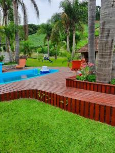 une cour avec une terrasse en bois et des palmiers dans l'établissement Casarão Biazolli, à Farroupilha