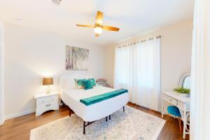 um quarto branco com uma cama e uma ventoinha de tecto em East Hill Vibes em Pensacola