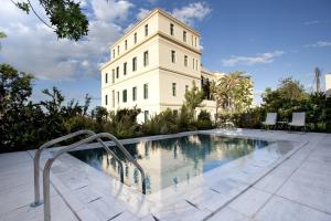 a building with a swimming pool in front of a building at Poseidonion Grand Hotel in Spetses