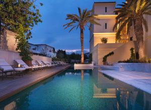 a swimming pool in front of a building with palm trees at Poseidonion Grand Hotel in Spetses