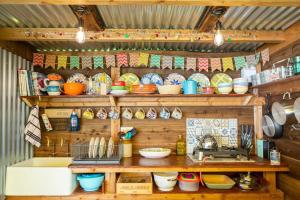 a kitchen with wooden shelves filled with bowls and plates at Orion 4-Person Stunning Lotus Belle Tent in Ross on Wye
