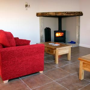 a living room with a red couch and a fire place at Coddy's Farm in Holmfirth