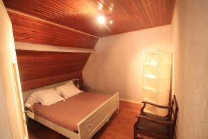 ein kleines Schlafzimmer mit einem Bett und einer Holzdecke in der Unterkunft Maison spacieuse au cœur de Queyssac avec jardin in Queyssac