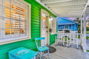 une maison verte avec une porte blanche et des chaises sur une terrasse couverte dans l'établissement Quaint Modern Downtown Cottage, à Saint Augustine