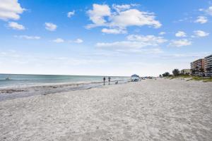 a beach with people standing on the sand and the ocean at Pelican Pointe 2C in Clearwater Beach