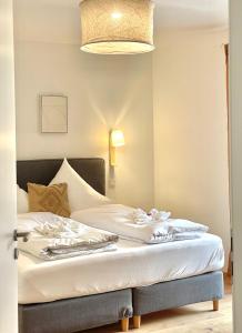 a bedroom with two beds with white sheets and a lamp at Hochfelder Traumsuite am Tegernsee in Tegernsee