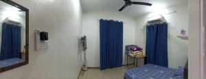 una camera ospedaliera con tende blu e specchio di Ainaz Homestay Balik Pulau a Balik Pulau
