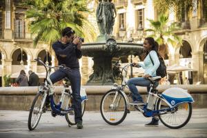
a man riding a bike next to a woman on a sidewalk at Oriente Atiram in Barcelona
