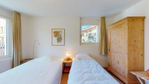 a bedroom with two beds and a dresser and two windows at Abitaziun Bellaval 1A - Celerina in Celerina