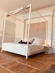un letto a baldacchino bianco in una camera da letto con pavimento in legno di l'Albuconis7 Appartement 160m2 ad Aubusson