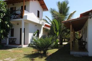 a white house with palm trees in front of it at Family Guest House in Ilha de Boipeba