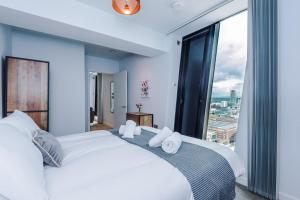 um quarto com uma grande cama branca e uma grande janela em Hilltop Serviced Apartments - Deansgate em Manchester