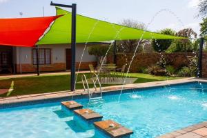 uma piscina com um guarda-sol verde e vermelho em Khanyisa Lifestyle em Vereeniging