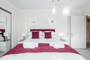 ein weißes Schlafzimmer mit einem großen weißen Bett mit roten Kissen in der Unterkunft Roomspace Serviced Apartments - Royal Swan Quarter in Leatherhead