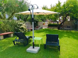 two chairs and an umbrella in a yard at B&B Maison Villa Vittorio in Avella