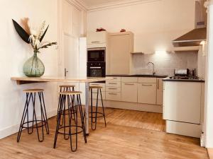 una cucina con armadietti bianchi e sgabelli da bar di l'Albuconis7 Appartement 160m2 ad Aubusson