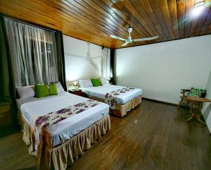Dos camas en una habitación con suelo de madera. en Hotel Casa Tago, en Alajuela