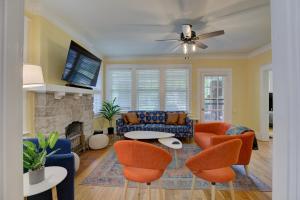 a living room with orange chairs and a fireplace at Spacious Bungalow with 6 Beds, Games, and Fire Pit - Close to Beale Street, BBQ, Graceland, & Liberty Bowl in Memphis