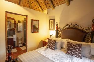 1 dormitorio con 1 cama grande y espejo en Indalu Game Reserve, en Boggomsbaai