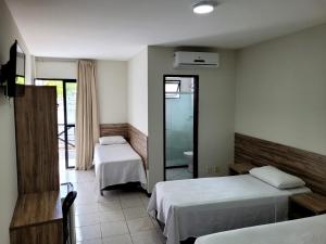 a hotel room with two beds and a mirror at Pousada Solaris in Salvador