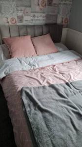 an unmade bed with pink pillows on it at Beautiful 2-Bed Chalet in Aberystwyth in Aberystwyth