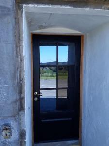 a black door with a view of a field at La Poudrière : lieu insolite, havre de paix in Vielsalm