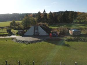 un pequeño edificio de piedra en un campo con patio en La Poudrière : lieu insolite, havre de paix en Vielsalm