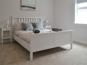 Una cama blanca en un dormitorio blanco con una mesa blanca en Devon Hill, en Glenluce