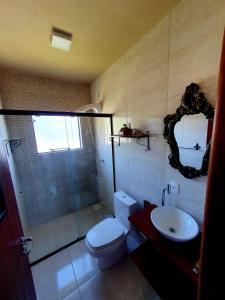 a bathroom with a toilet and a sink and a mirror at Chalé da Montanha com Ofurô in Santo Amaro da Imperatriz