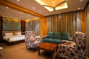 a living room with a bed and a couch and chairs at Eden Park Boutique Hotel in Vijayawāda