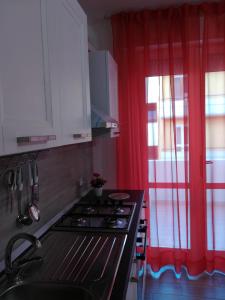 uma cozinha com um fogão e uma cortina vermelha em Sweet Home QSE em Quartu SantʼElena
