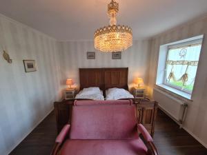 ein Schlafzimmer mit einem Bett, einem Kronleuchter und einem Stuhl in der Unterkunft Überfahrt vor Sylt in Klanxbüll