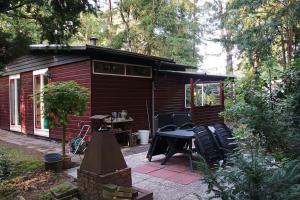 a small cabin with a table and chairs in front of it at Bosbungalow de Eekhoorn in Nunspeet